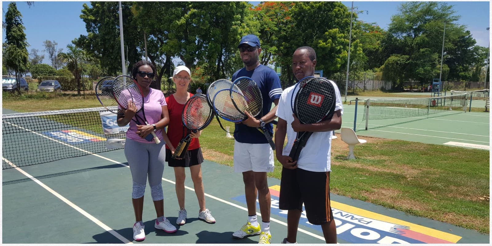 Four players holding their newly donated racquets on a court in Dar es Salaam