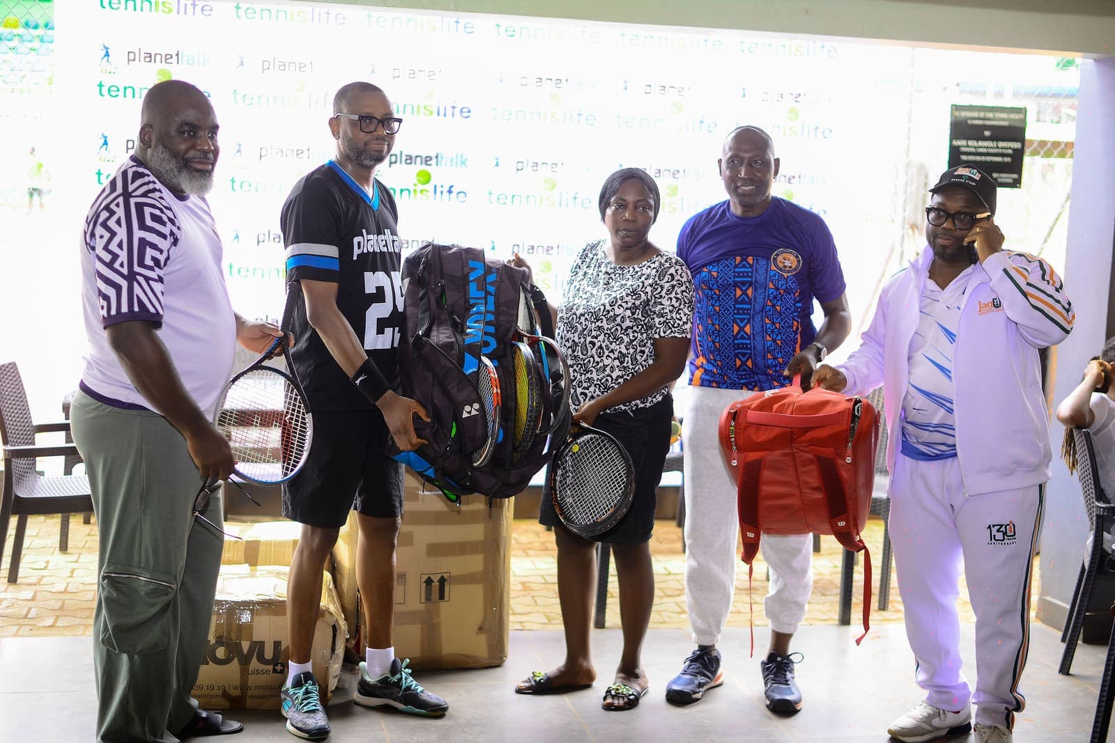 Trustees and TPPA representatives holding donated racquets and bags in front of the TennisIsLife backdrop